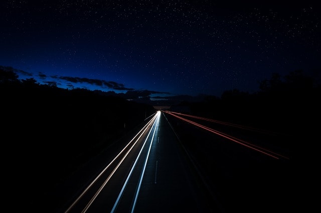 Autostrada di notte, scie di luce, macchine veloci, distanze.