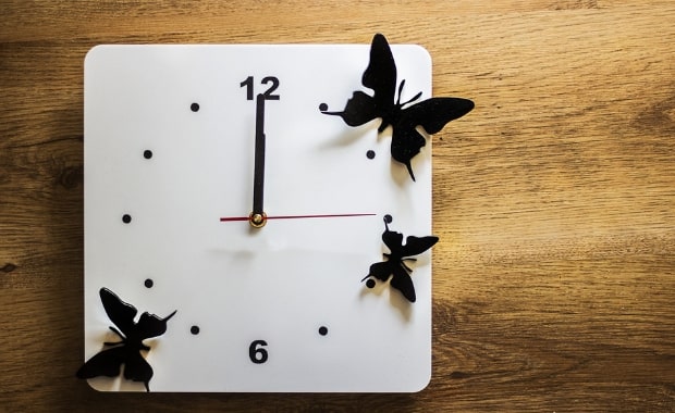 Orologio moderno indicante la mezzanotte o il mezzogiorno, bianco e decorato con tre farfalle.