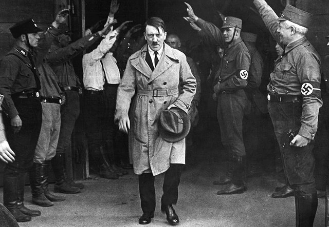 adolf hitler mentre sta uscendo dalla sede del partito nazista a monaco nel 1931, accompagnato dal saluto nazista