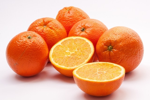 Sei arance, arancia tagliata a metà.