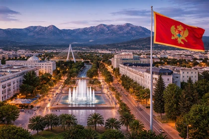 Podgorica, capitale del Montenegro, con la bandiera nazionale e il centro città al tramonto