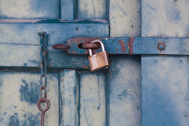 Porta di legno blu turchese chiusa, catena, lucchetto, ruggine.