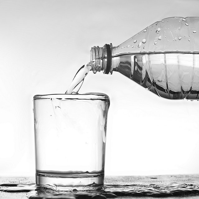 Bottiglia riempie un bicchiere d'acqua, bianco, artistico.