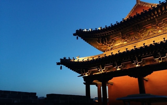 Vista notturna di un palazzo cinese. Luce, mura, cielo.
